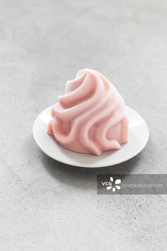素食石榴冰霜，呈法式香草奶油的形状，摆放在盘子上图片素材