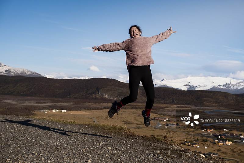 年轻女性在山景中欢快地跳跃图片素材