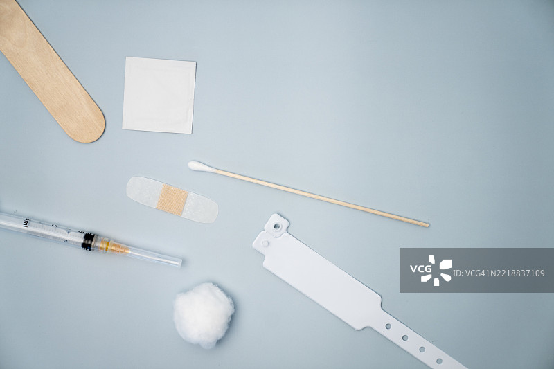 蓝色背景上的医疗用品，包括注射器、棉花、绷带和腕带图片素材