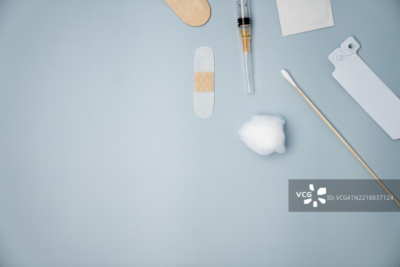 蓝色背景上的医疗用品，包括注射器、棉花、绷带和腕带图片素材