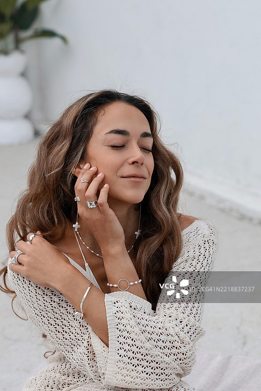 微笑的女性穿着时尚的银色珠宝和钩针裙。图片素材