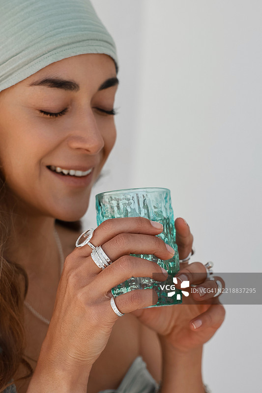 女人享受清爽饮品，佩戴时尚戒指，面带宁静表情图片素材