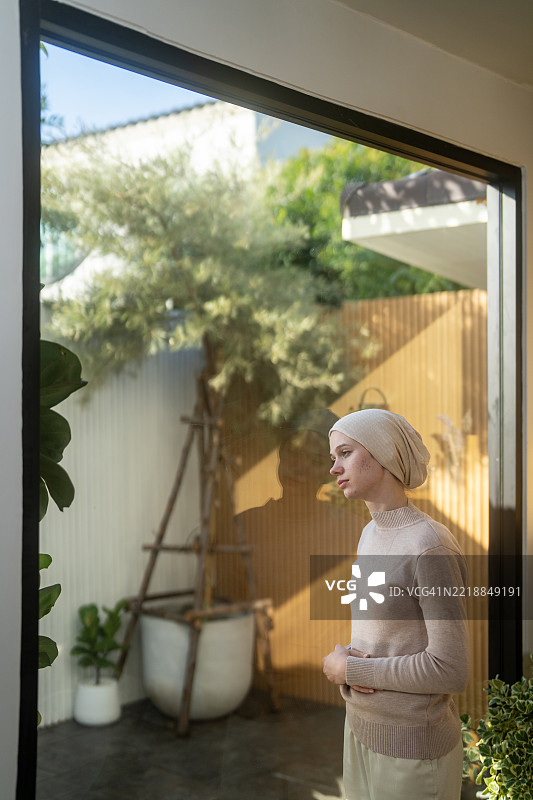 年轻的癌症患者感到不适，望着窗外。图片素材