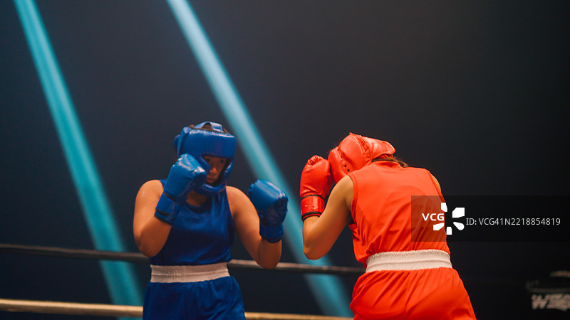 两名亚洲女性拳击手在裁判示意开始时准备开打。图片素材