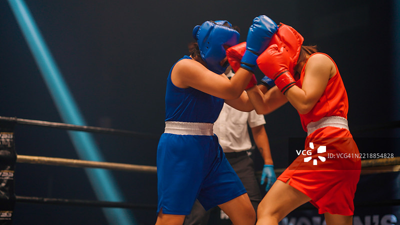 两名亚洲女性拳击手在裁判的信号下开始比赛。图片素材