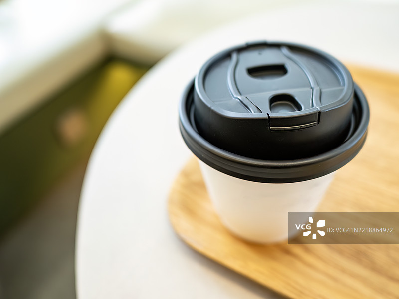 木托盘上的外带咖啡杯在柔和的光线下图片素材