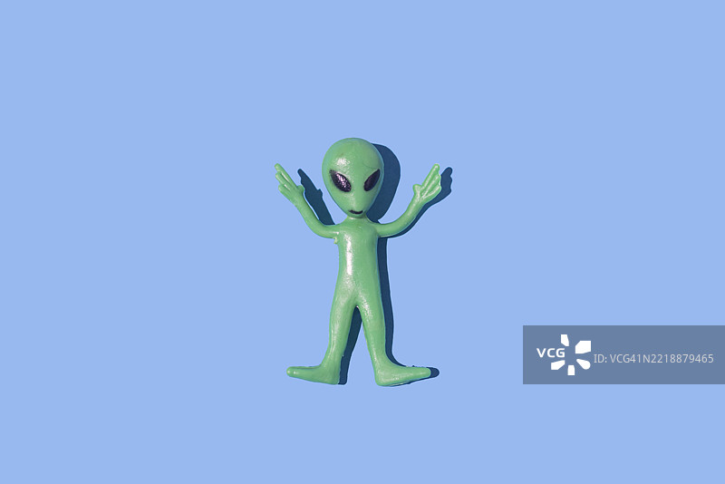 绿色外星人玩具模型，背景为纯蓝色。外星生物，虚构，科幻，恐怖，罗斯威尔，51区，飞碟学，飞碟。图片素材