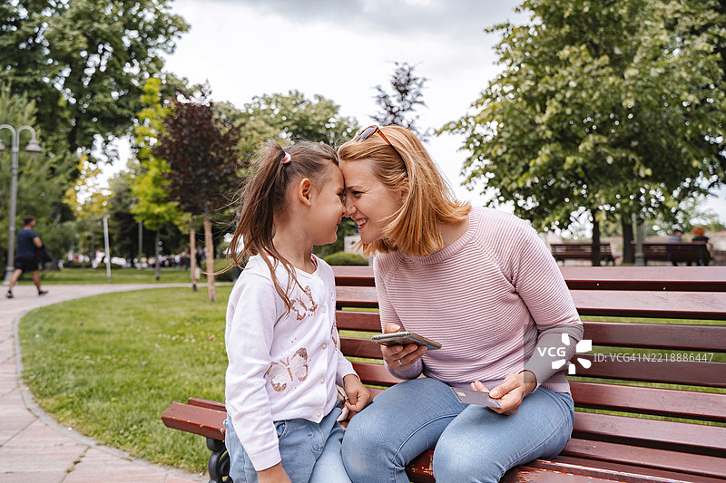 母女在公园使用智能手机和信用卡在线购物图片素材