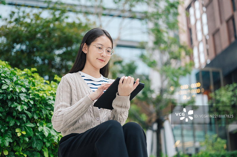 快乐的亚洲Z世代在手机应用上微笑着浏览投资组合，查看加密货币价格和市场动态。图片素材