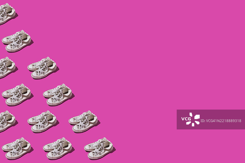 旧款磨损的复古风格白色篮球鞋的图案，位于左侧，背景为粉色。现代、时尚、复古、篮球、运动、休闲和非正式鞋类概念。图片素材