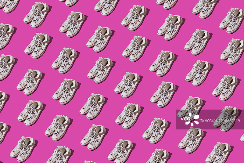 旧款磨损的复古风格白色篮球鞋在粉色背景上的图案。现代、时尚、复古、篮球、运动、休闲和非正式鞋类概念。图片素材