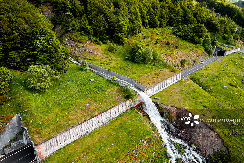 法国比利牛斯山脉森林公路隧道上方的瀑布鸟瞰图 - 可持续基础设施促进环保交通图片素材