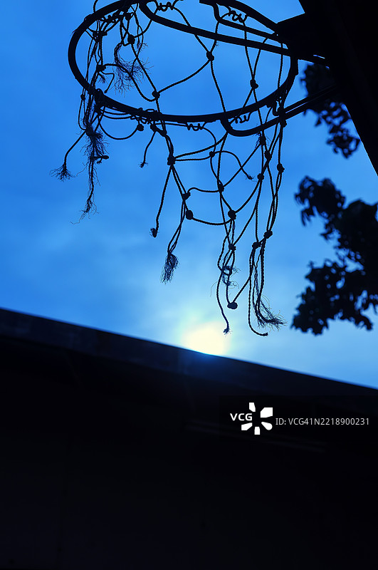 一个低角度拍摄的破旧篮球架，背景是明亮的天空。图片素材