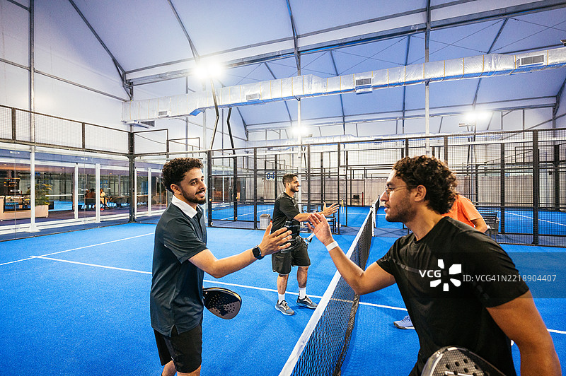 一群技术娴熟的壁球运动员在室内新场地进行比赛，比赛结束后握手致意。图片素材