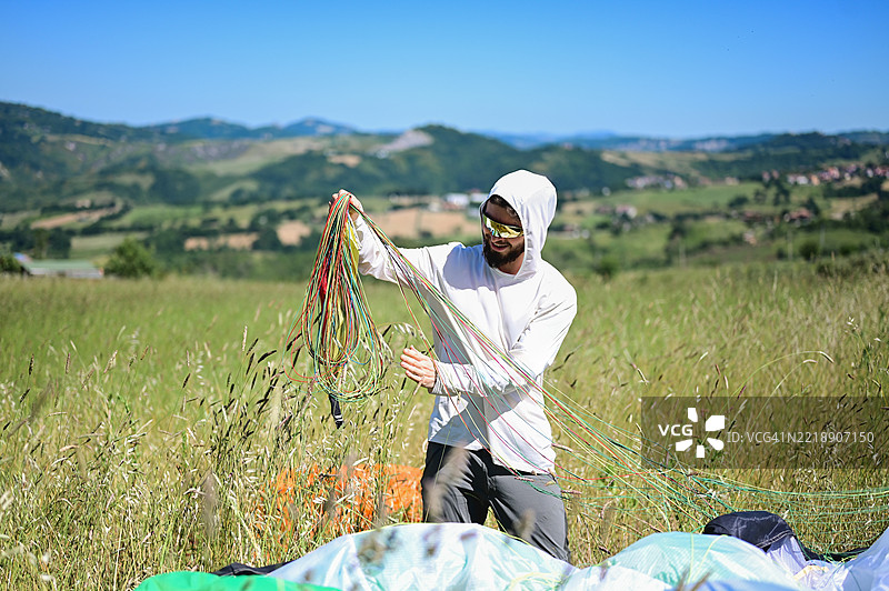 滑翔伞运动员在起飞后在田野中理顺绳索并准备设备图片素材