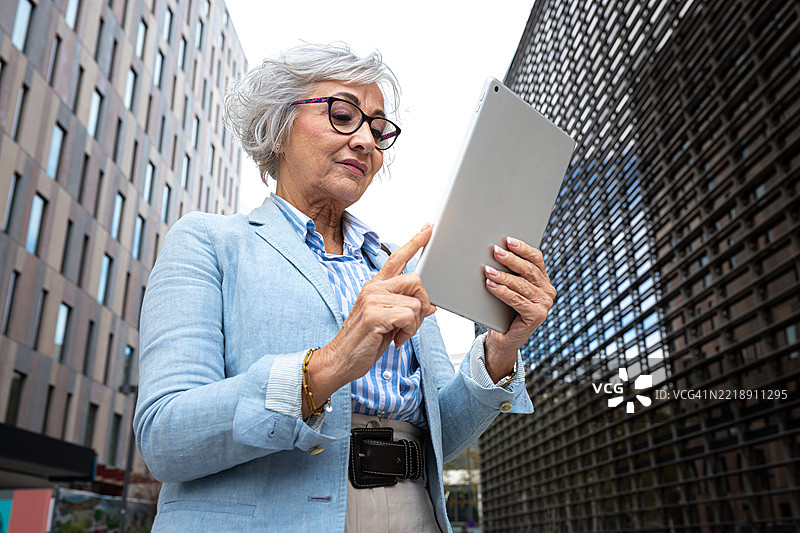 城市环境中使用数字平板的资深女商人图片素材