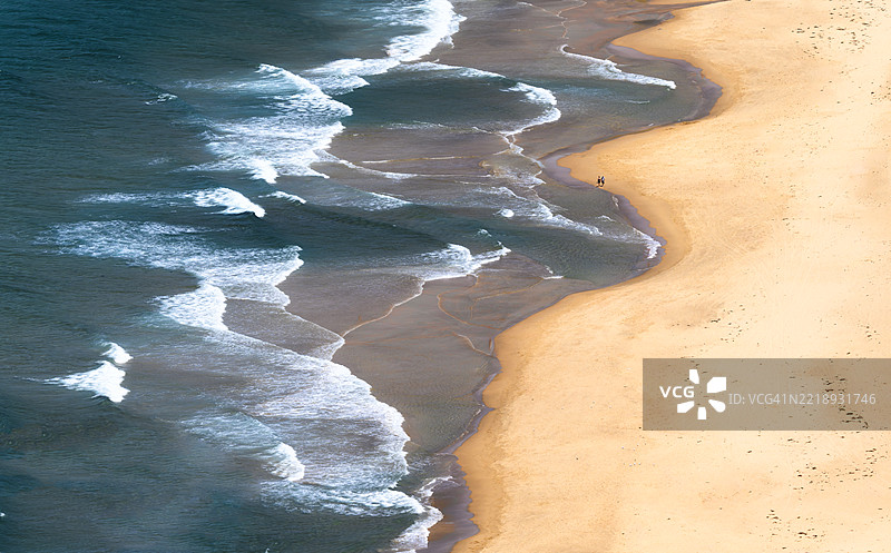 一对恋人在海滩上漫步的鸟瞰图图片素材