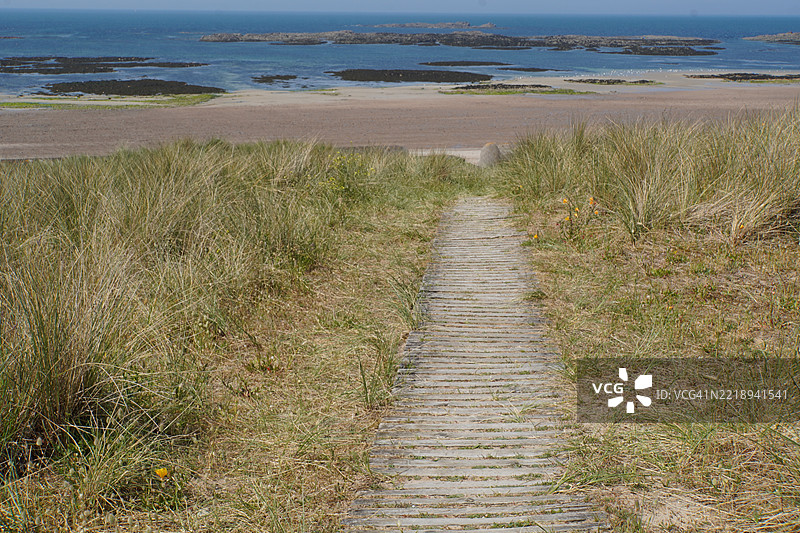 通往海滩的木栈道，蓝色的海洋和蓝色的天空图片素材