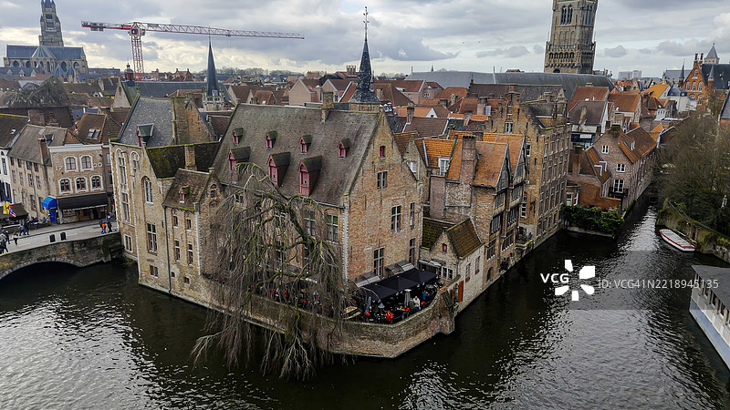 布鲁日蜿蜒运河的鸟瞰图，历史悠久的弗拉芒房屋与红色屋顶和阶梯式山墙沿着宁静的鹅卵石街道排列，联合国教科文组织列入的中世纪城市，旅行与建筑遗产概念图片素材