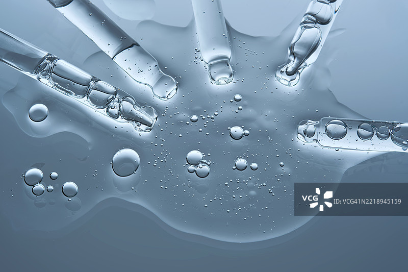 血清从几个移液管流入蓝色背景上的单一纹理中图片素材