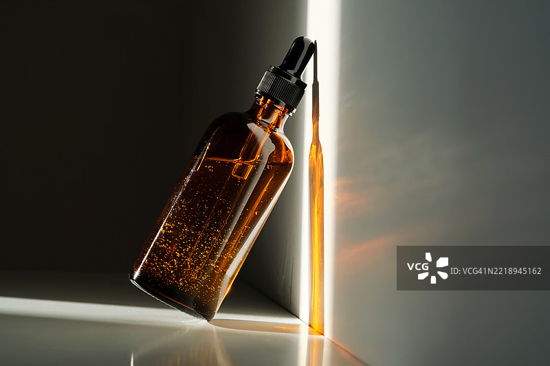 一瓶棕色玻璃制成的精华液，背景为白色，带有光线条纹。图片素材