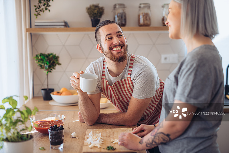 朋友们在厨房一起做晚餐，准备食材。图片素材