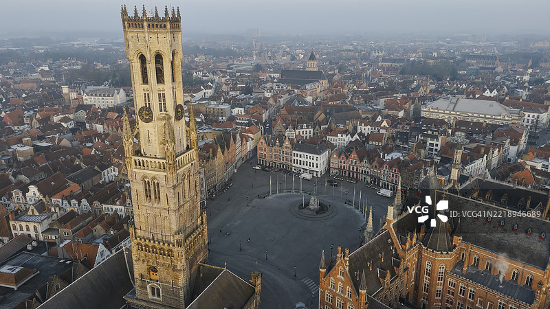 布鲁日钟楼和历史悠久的市场广场在日出时的鸟瞰图，标志性的中世纪钟楼和弗拉芒建筑，城市遗产与旅行设计概念，温暖晨光下的全景城市风光图片素材