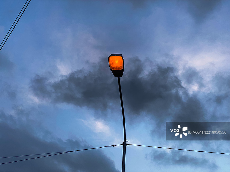 街灯在下午的蓝天映衬下发出橙色的光芒图片素材