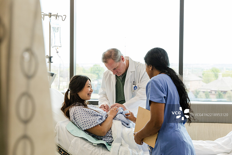 医生和护士祝贺快乐的新妈妈和她的新生儿图片素材