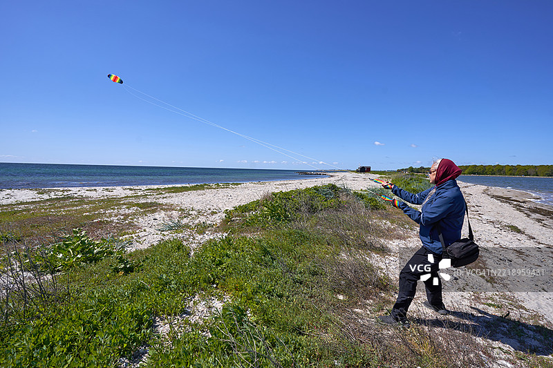 一位女性在波罗的海的厄尔岛马尔斯塔尔海滩上操控特技风筝图片素材
