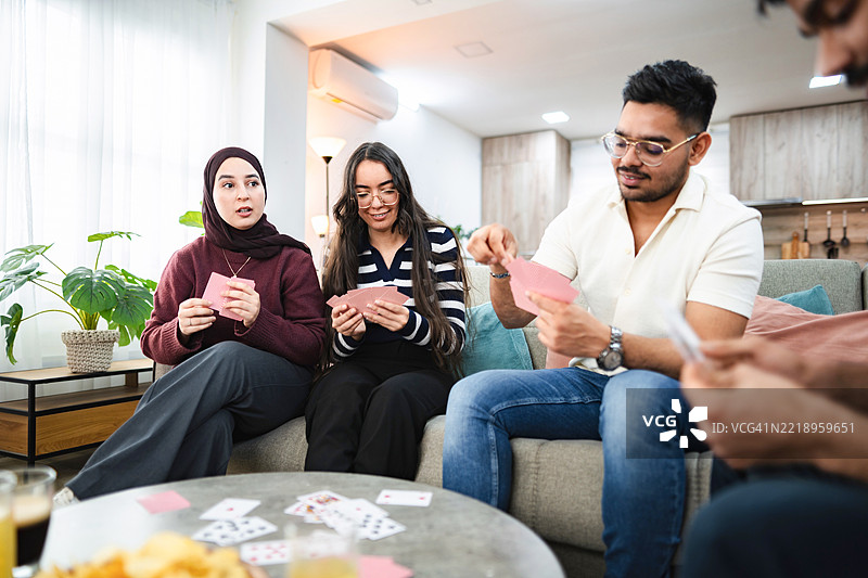 快乐的朋友们在家里一起玩牌，享受欢乐时光图片素材