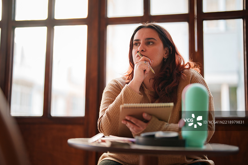 在咖啡馆用铅笔在素描本上绘画的女性图片素材