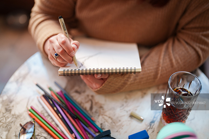 在咖啡馆用铅笔在素描本上绘画的女性图片素材