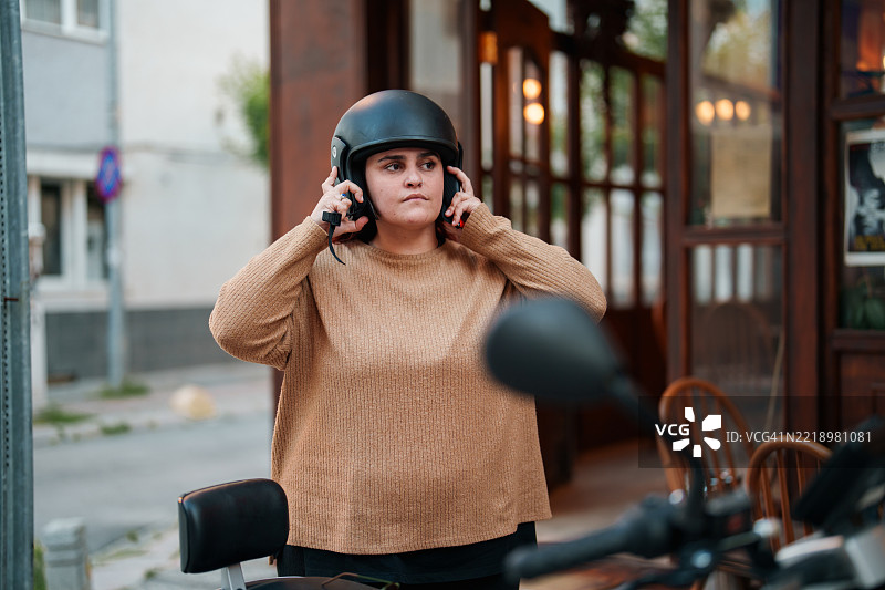 年轻女性骑着滑板车，戴上头盔图片素材