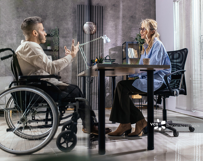 一位坐在轮椅上的年轻人来到雇主面前寻找工作。图片素材