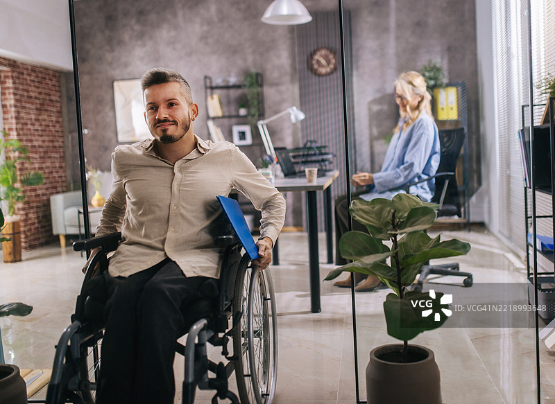 一位坐在轮椅上的年轻人来到雇主面前寻找工作。图片素材