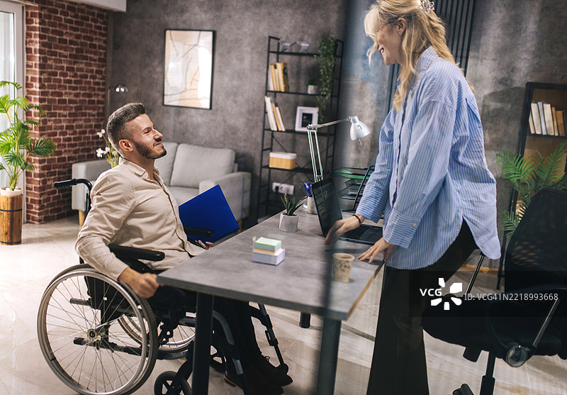 一位坐在轮椅上的年轻人来到雇主面前寻找工作。图片素材