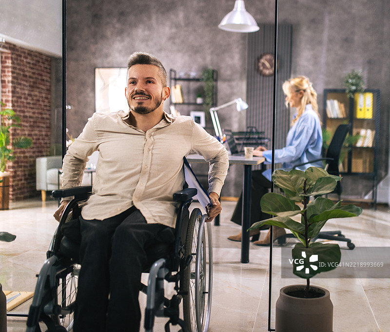 一位坐在轮椅上的年轻人来到雇主面前寻找工作。图片素材