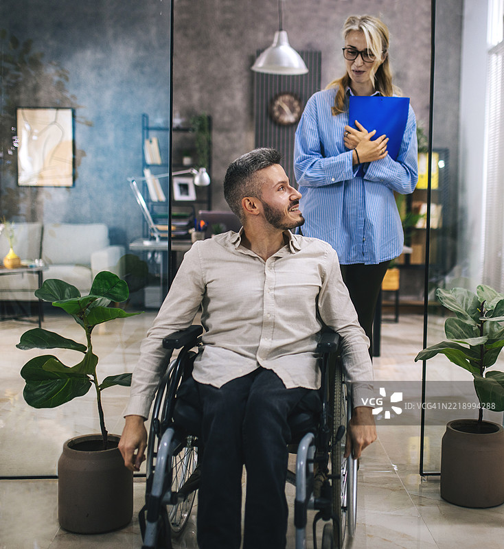 一位坐在轮椅上的年轻人来到雇主面前寻找工作。图片素材