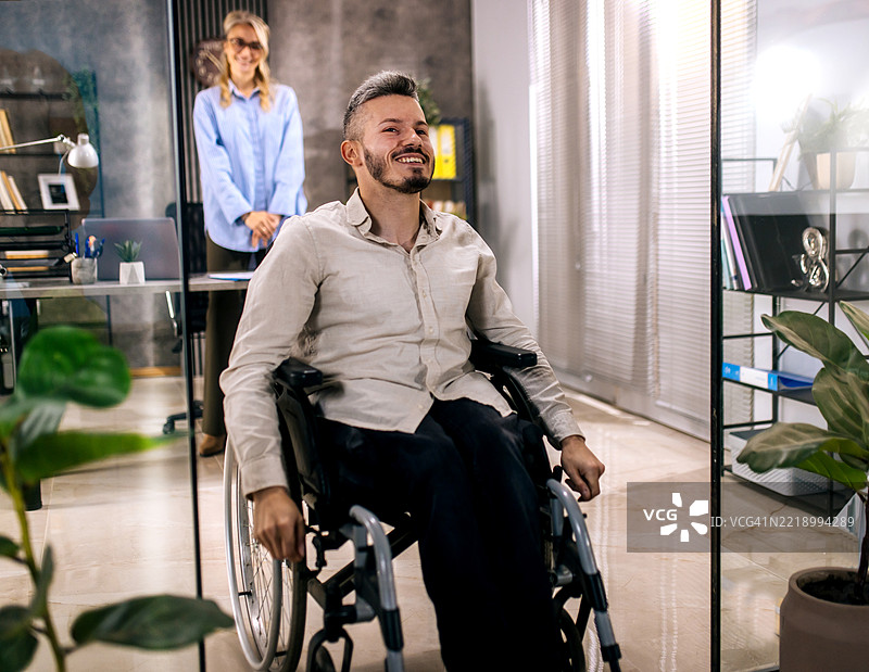 一位坐在轮椅上的年轻人来到雇主面前寻找工作。图片素材