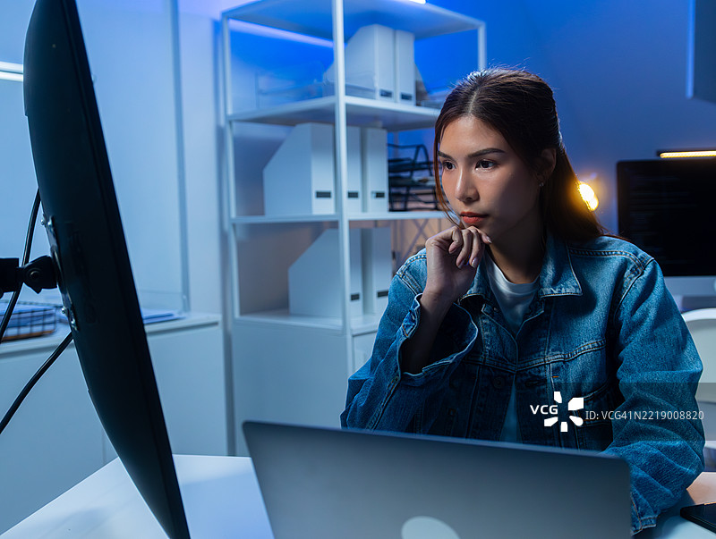 亚洲女性自由职业软件开发者正在分析屏幕上的源代码算法。图片素材