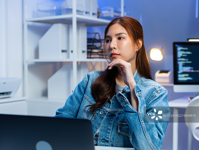 亚洲女性自由职业软件开发者正在分析屏幕上的源代码算法。图片素材