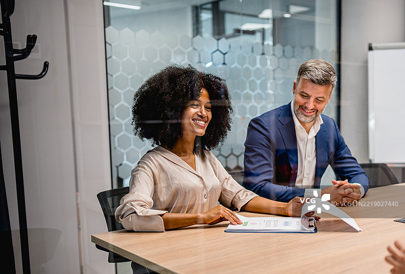 微笑的女商人正在办公室与男性同事讨论商业策略图片素材
