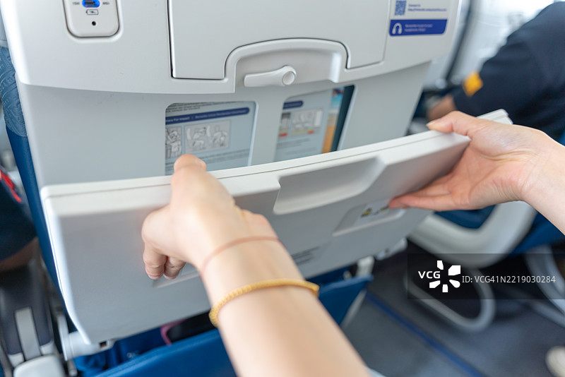 一位亚洲乘客正在使用飞机上的小桌子。图片素材