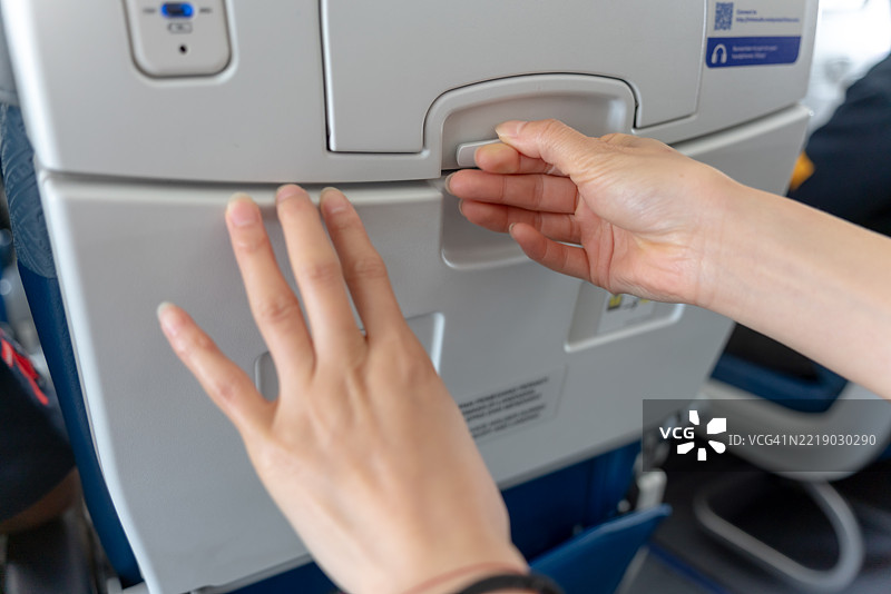 一位亚洲乘客正在使用飞机上的小桌子。图片素材