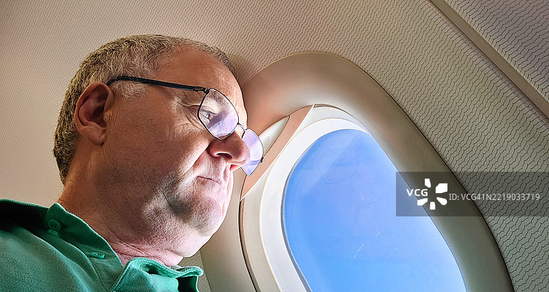 游客透过飞机窗户眺望。图片素材