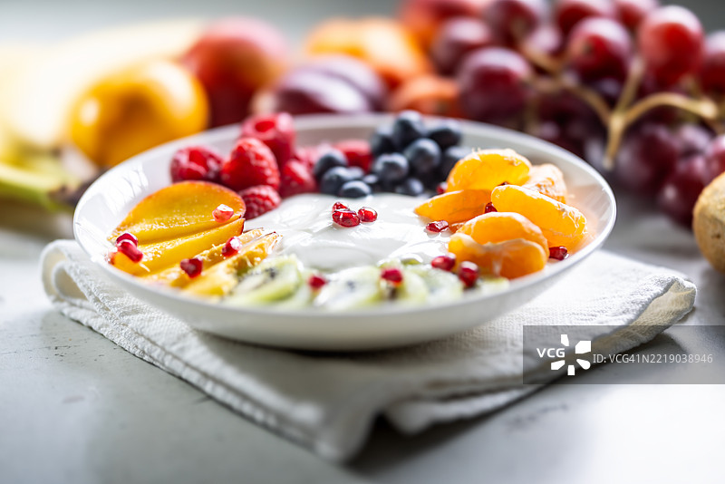 一碗装满原味酸奶的水果，包括蓝莓、覆盆子、猕猴桃、油桃、橘子和石榴籽图片素材