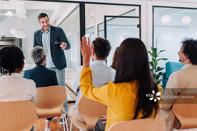 一位女商人在研讨会上想要提问的背影。图片素材