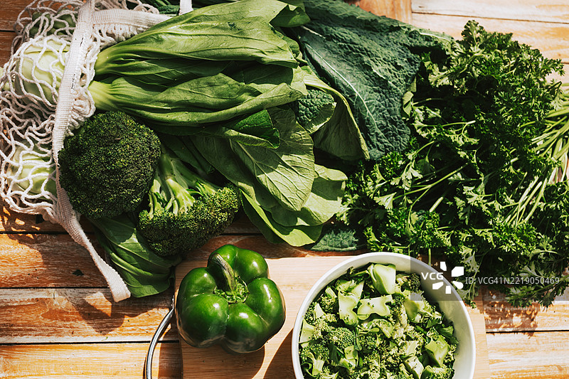 新鲜的生菜叶、凯尔、青椒和西兰花放在木桌上。用于烹饪的农场绿色蔬菜。图片素材