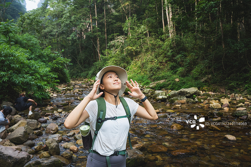 一位穿着运动服的亚洲女性正在户外溪流中徒步旅行图片素材